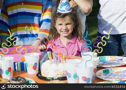 Portrait of a girl standing in front of a birthday cake