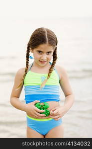 Portrait of a girl standing on the beach and holding a toy