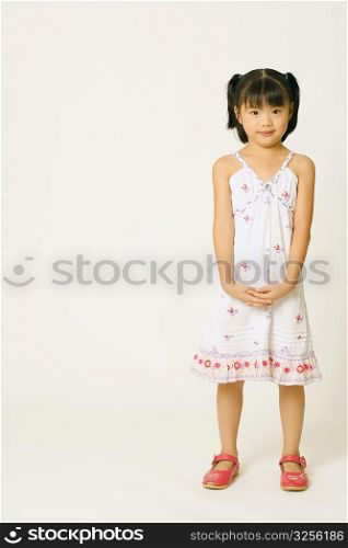 Portrait of a girl standing with her hands clasped