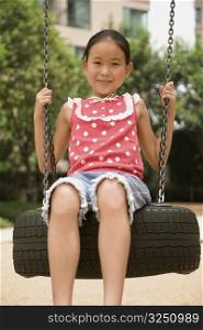 Portrait of a girl swinging on a tire swing