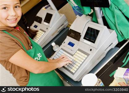 Portrait of a girl using a cash register at the checkout counter and smiling