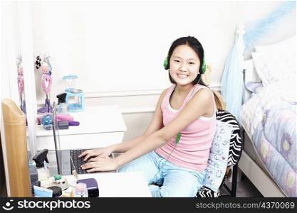 Portrait of a girl using a laptop and listening to music