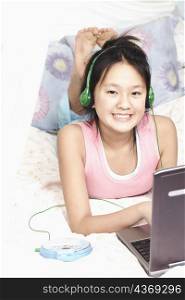Portrait of a girl using a laptop and listening to music on an MP3 player
