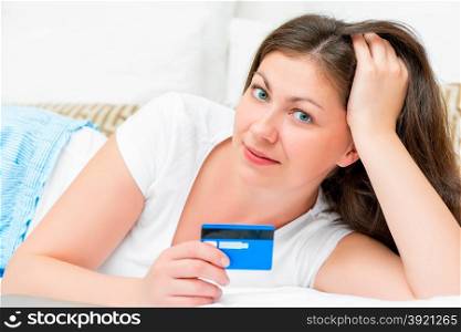 portrait of a girl with a credit card lying on a bed