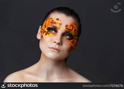Portrait of a girl with an original make-up. Beauty close-up. Orange and red rhinestones on a face. Girl with orange and red rhinestones on her face.