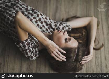 Portrait of a girl with flowing hair lying on the floor.. The girl lay on the parquet floor, arms outstretched 6964.