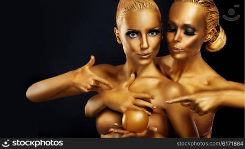 Portrait of a girl with golden body art posing with golden apple in her hands.