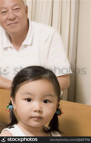 Portrait of a girl with her grandfather sitting behind her