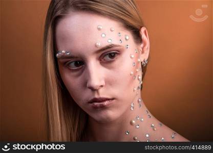 Portrait of a girl with original and creative makeup with white and pearl rhinestones. Girl with white and pearl rhinestones on her face.
