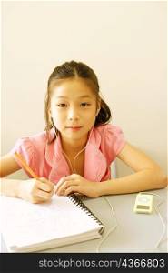 Portrait of a girl writing a spiral notebook and listening to an MP3 player