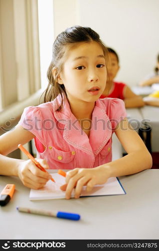 Portrait of a girl writing in a spiral notebook in the classroom