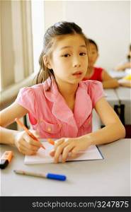 Portrait of a girl writing in a spiral notebook in the classroom