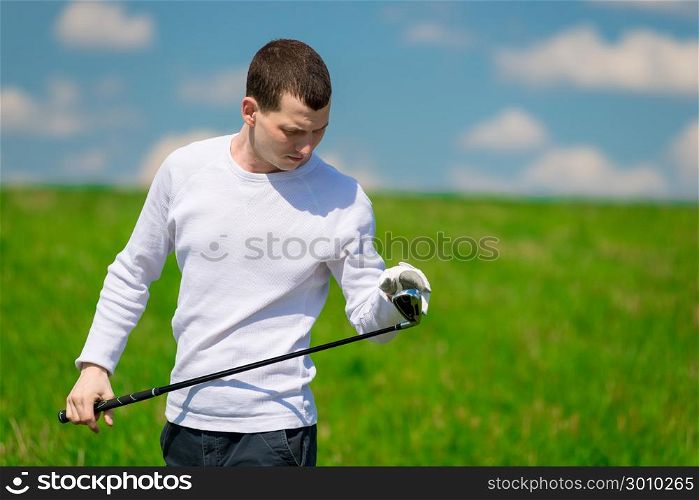 portrait of a golfer inspecting his golf club before playing on the field
