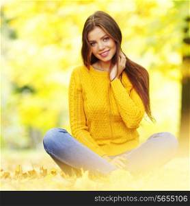 Portrait of a gorgeous brunette woman sitting in the autumn park