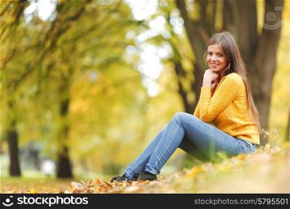 Portrait of a gorgeous brunette woman sitting in the autumn park. Woman in autumn park