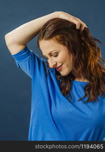 Portrait of a gorgeous smiling woman with red hair over blue background.