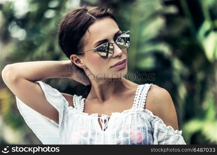 Portrait of a gorgeous woman in rainforest, attractive sexy model wearing stylish sunglasses, enjoying summer vacation in tropical islands. Fashion woman portrait