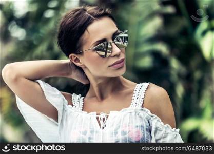 Portrait of a gorgeous woman in rainforest, attractive sexy model wearing stylish sunglasses, enjoying summer vacation in tropical islands. Fashion woman portrait