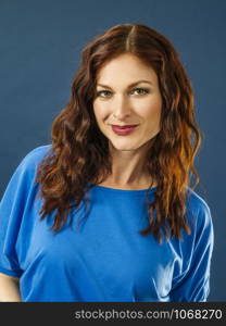 Portrait of a gorgeous woman with red hair over blue background.