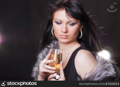 Portrait of a gorgeous young brunette with glass of sparkling wine on the black background. Woman with glass of sparkling wine
