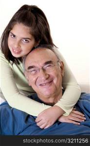 Portrait of a granddaughter hugging her grandfather from behind