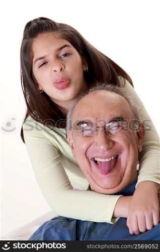 Portrait of a granddaughter sticking out her tongue and hugging her grandfather