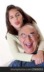 Portrait of a granddaughter sticking out her tongue and hugging her grandfather