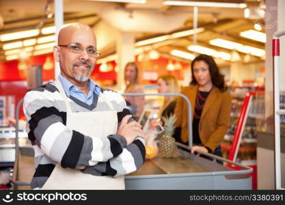 Portrait of a grocery store cashier standing at a checkout counter