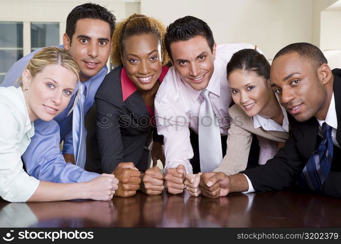 Portrait of a group of business executives pounding their fists on a conference table