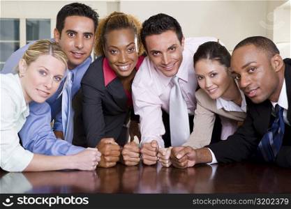 Portrait of a group of business executives pounding their fists on a conference table