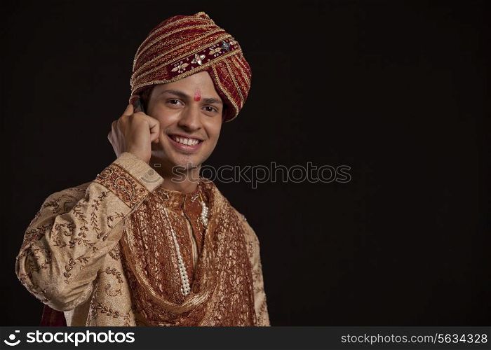 Portrait of a Gujarati groom talking on a mobile phone