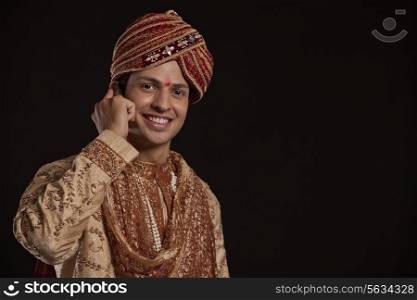 Portrait of a Gujarati groom talking on a mobile phone