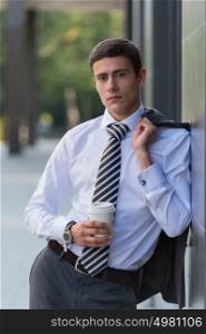 Portrait of a handsome businessman drinking coffee on the street near office building