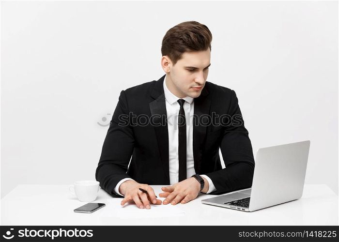 Portrait of a handsome businessman holding smartphone while working on a computer at his desk. He is in a office his notebook in front of him like an insurance or bank manager. Portrait of a handsome businessman holding smartphone while working on a computer at his desk. He is in a office his notebook in front of him like an insurance or bank manager.