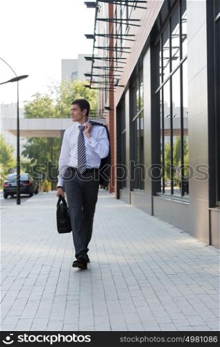 Portrait of a handsome businessman walking on the street near office building
