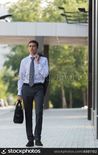 Portrait of a handsome businessman walking on the street near office building