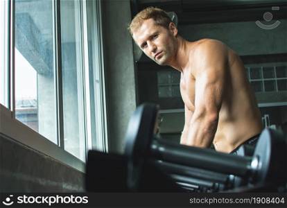 Portrait of a handsome muscular man is lifting dumbbells in fitness or gym. Healthy and Lifestyle Concept.
