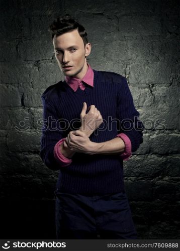 Portrait of a handsome stylish man against a brick wall. Fashion portrait of young man. Boy with modern hairstyle.