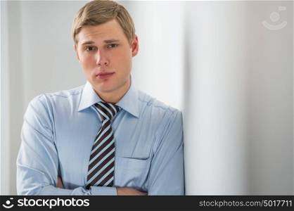 Portrait of a handsome young business man leaning against the wall