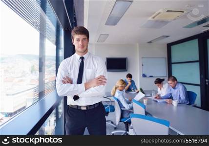 Portrait of a handsome young business man on a meeting in offce with colleagues in background