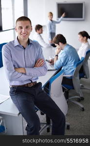 Portrait of a handsome young business man on a meeting in offce with colleagues in background