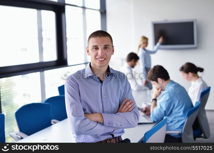 Portrait of a handsome young business man on a meeting in offce with colleagues in background