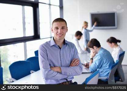 Portrait of a handsome young business man on a meeting in offce with colleagues in background