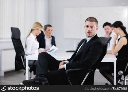 Portrait of a handsome young business man with people in background at office meeting
