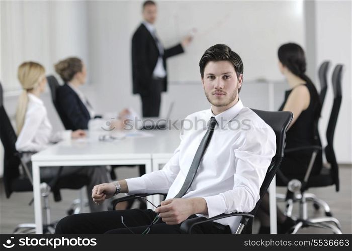 Portrait of a handsome young business man with people in background at office meeting