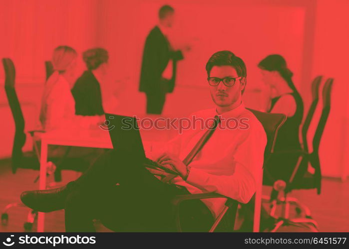 Portrait of a handsome young business man with people in background at office meeting