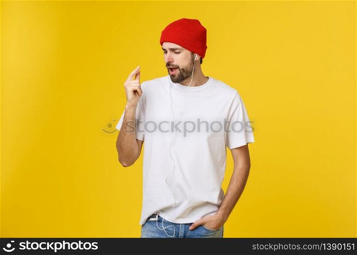 Portrait of a handsome young man dancing and listening music, isolated on yellow background.. Portrait of a handsome young man dancing and listening music, isolated on yellow background