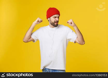 Portrait of a handsome young man dancing and listening music, isolated on yellow background.. Portrait of a handsome young man dancing and listening music, isolated on yellow background