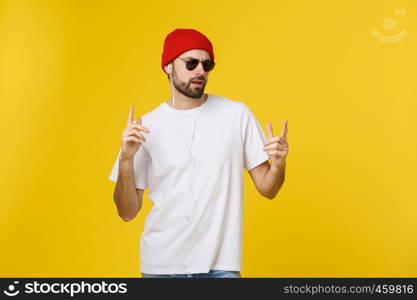 Portrait of a handsome young man dancing and listening music, isolated on yellow background.. Portrait of a handsome young man dancing and listening music, isolated on yellow background