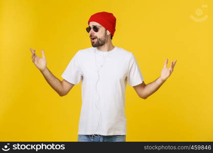 Portrait of a handsome young man dancing and listening music, isolated on yellow background.. Portrait of a handsome young man dancing and listening music, isolated on yellow background